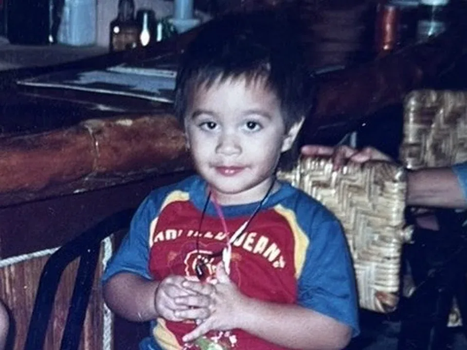Cole as a toddler, sitting on a woven chair