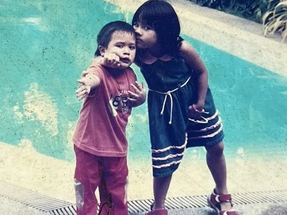 Cole as a small child beside a swimming pool with his sister