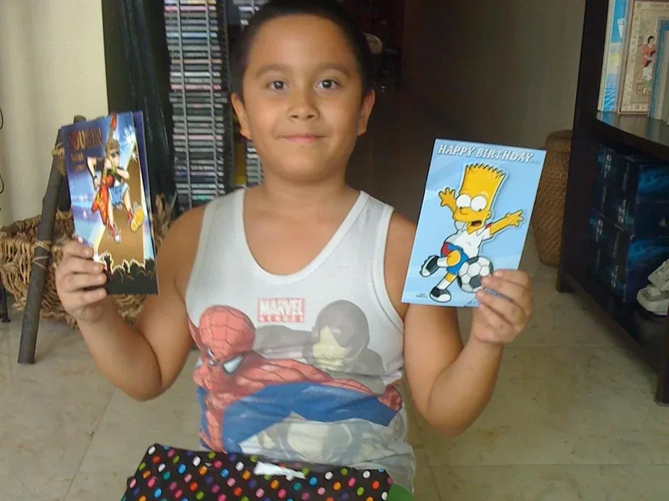 Cole as a boy holding up birthday cards